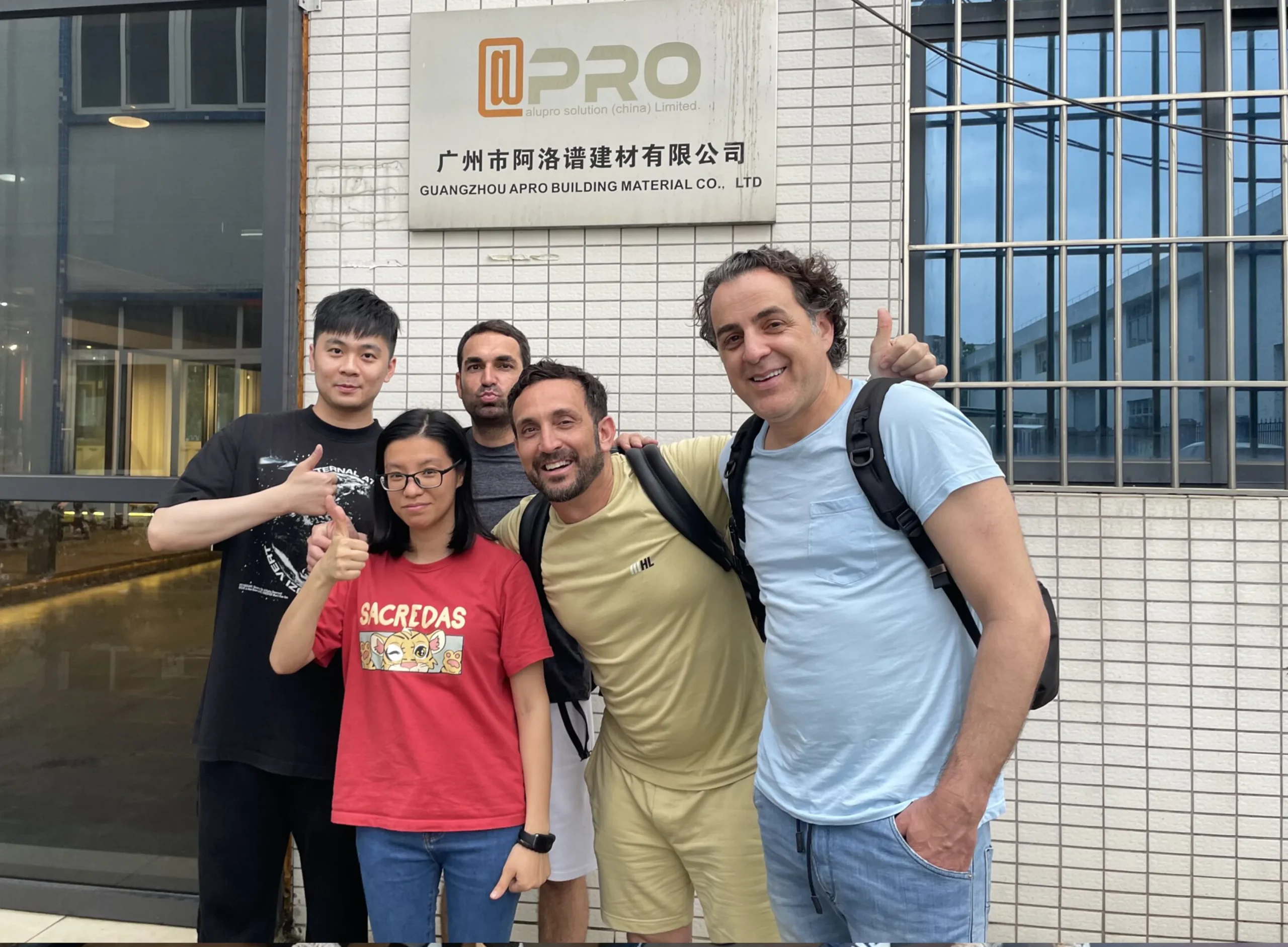 Nancy, a salesperson from Progolas & Aprodoor, and a customer took a photo in front of the factory sign.