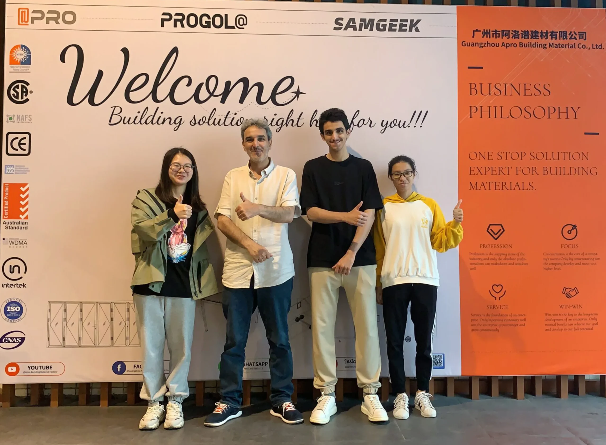 Nancy, a salesperson from Progolas & Aprodoor, took a photo with two foreign customers in front of the factory billboard.