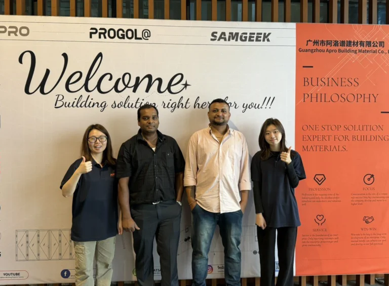 Progolas & Aprodoor и два иностранных клиента сфотографировались перед рекламным щитом компании.