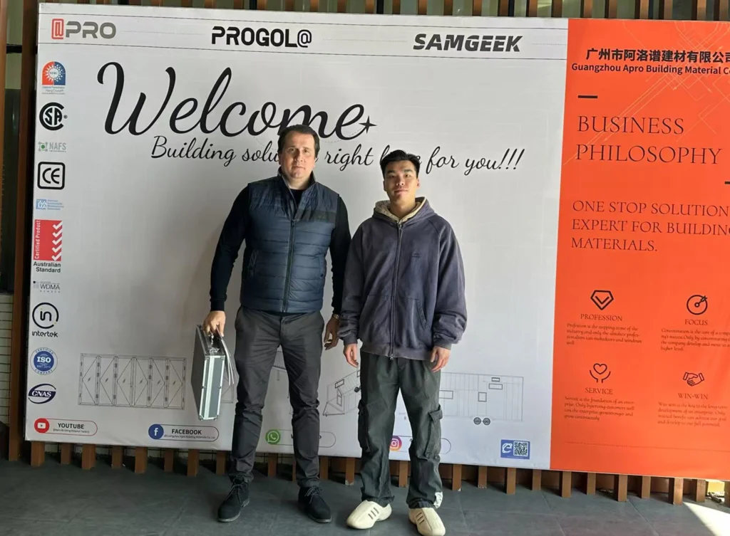 El vendedor de Progolas y Aprodoor, Chirs, y los clientes estadounidenses se tomaron una foto frente al cartel publicitario de la empresa.