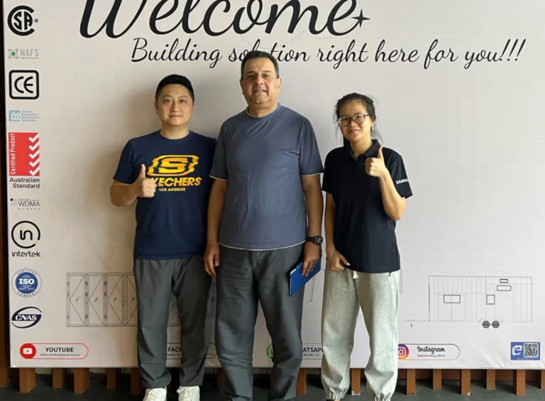 Владелец и продавец Progolas & Aprodoor сфотографировался с европейскими клиентами перед рекламным щитом компании.