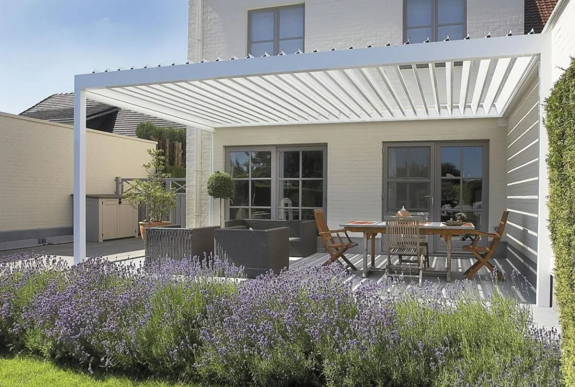 A white 1410 series electric awning installed at the back door of the house, with a dining table and chairs placed underneath A white 1410 series electric awning installed at the back door of the house, with a dining table and chairs placed underneath